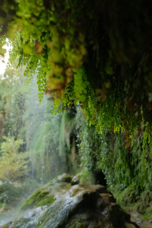 the view from inside of a stone structure at an outdoor waterfall