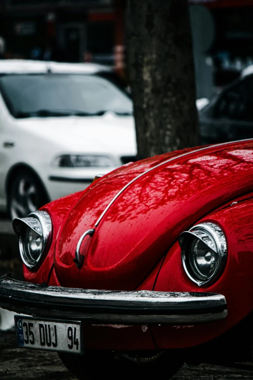 a red beetle is sitting outside on the side of a road