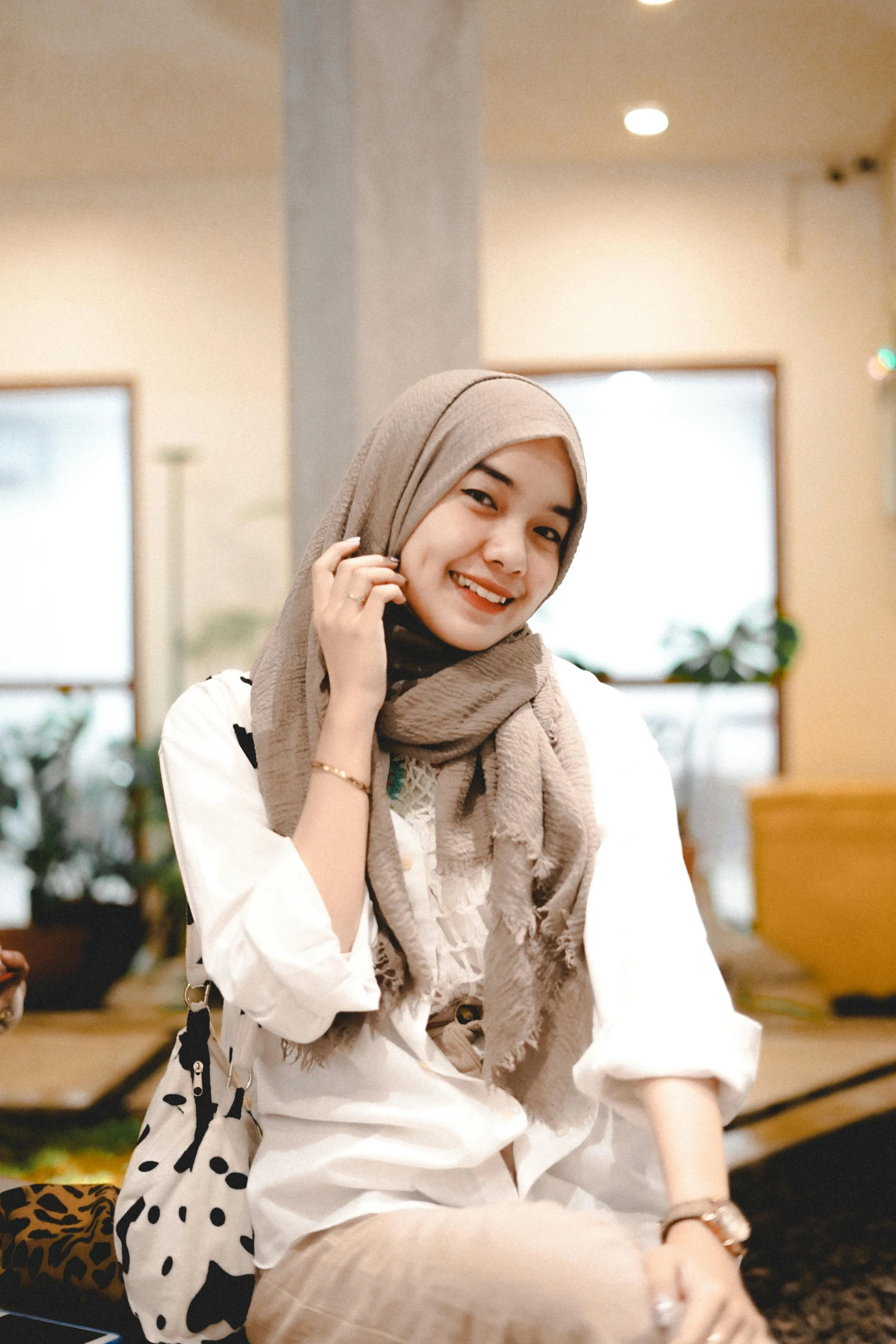 a woman with hijab sitting down talking on her cell phone