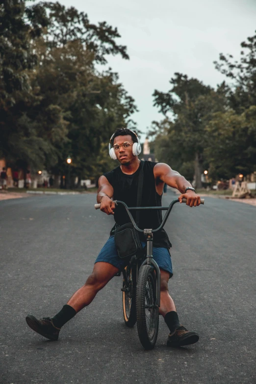 a man on a bicycle, wearing headphones, with trees in the background