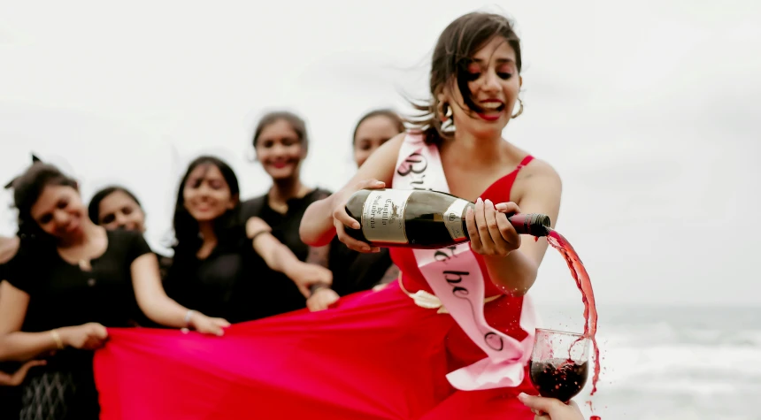 a woman in a pink dress holds a wine bottle