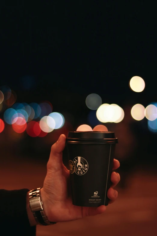 a person is holding a coffee cup at night