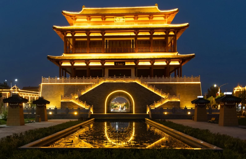 a lit up building at night in an area with a fountain