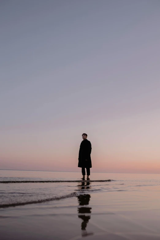 a person walking on the beach with the sun setting