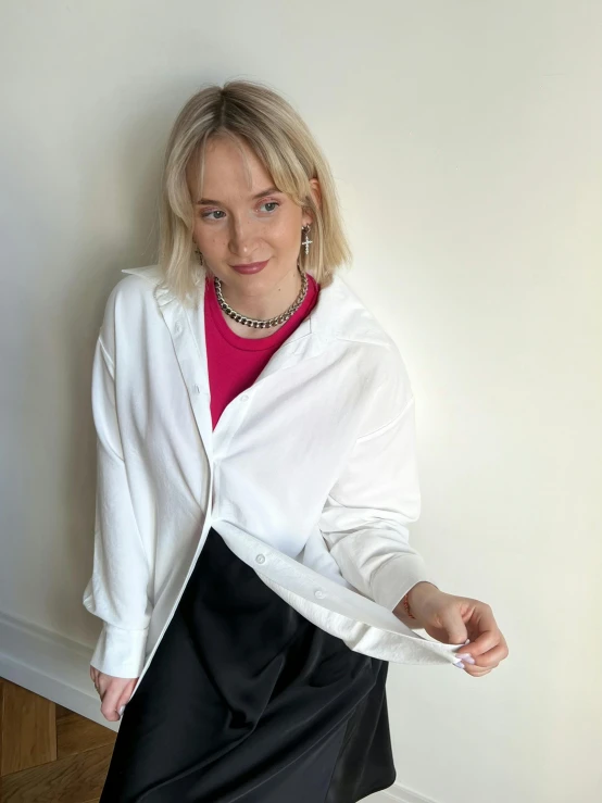 a woman wearing a black skirt, pink shirt and white jacket