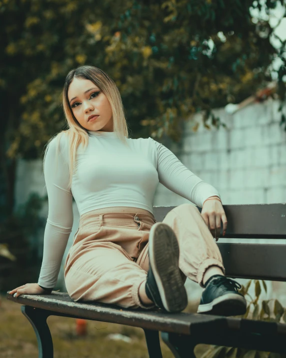 a woman sitting on top of a bench next to a tree