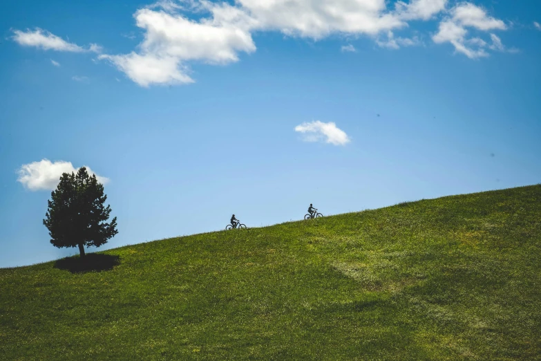 two people riding bikes on the side of a hill