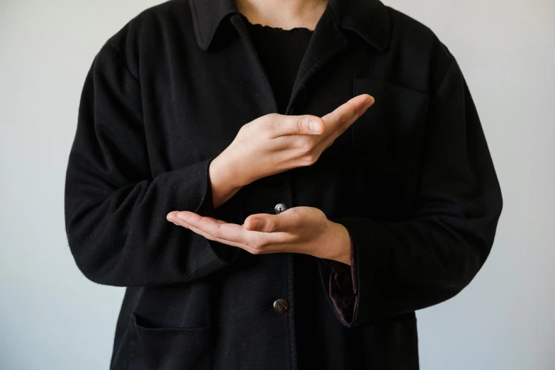 a man in a black jacket and black shirt making the hand sign
