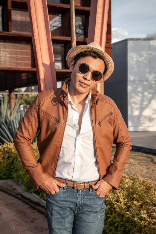 man wearing a tan jacket, sunglasses and straw hat