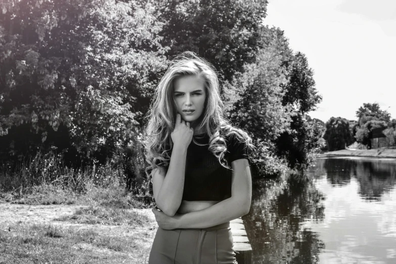 a young woman with long hair standing by a lake