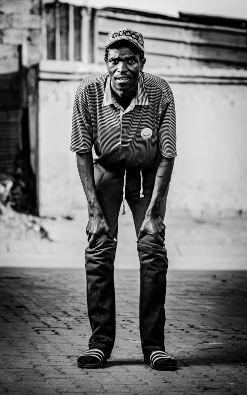 the man is standing sideways, leaning down on his skateboard