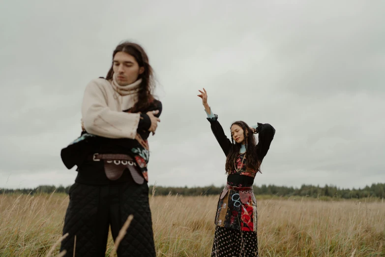 two women stand in the grass in a field