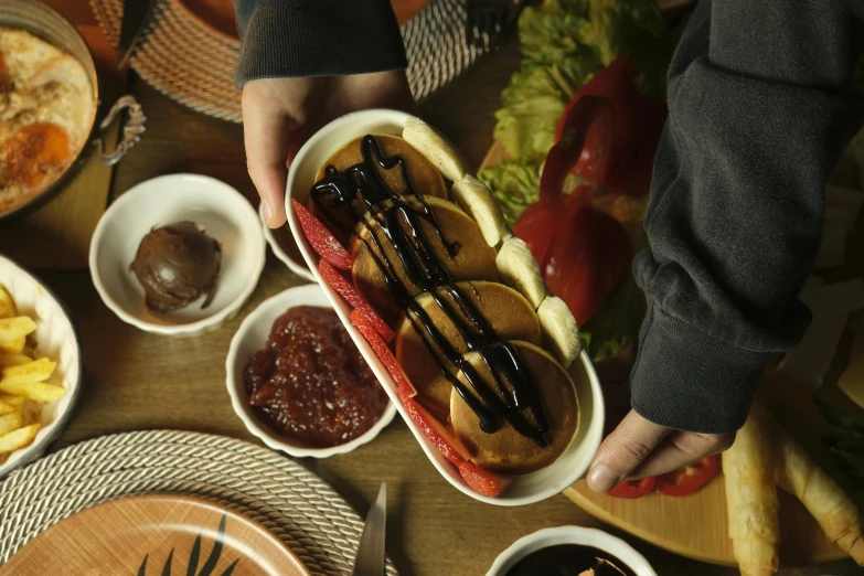 hands grabbing a  dog from a container with dipping sauce