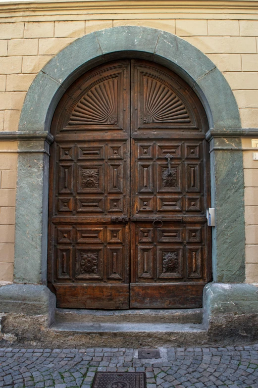 an arched wooden door has a brick wall