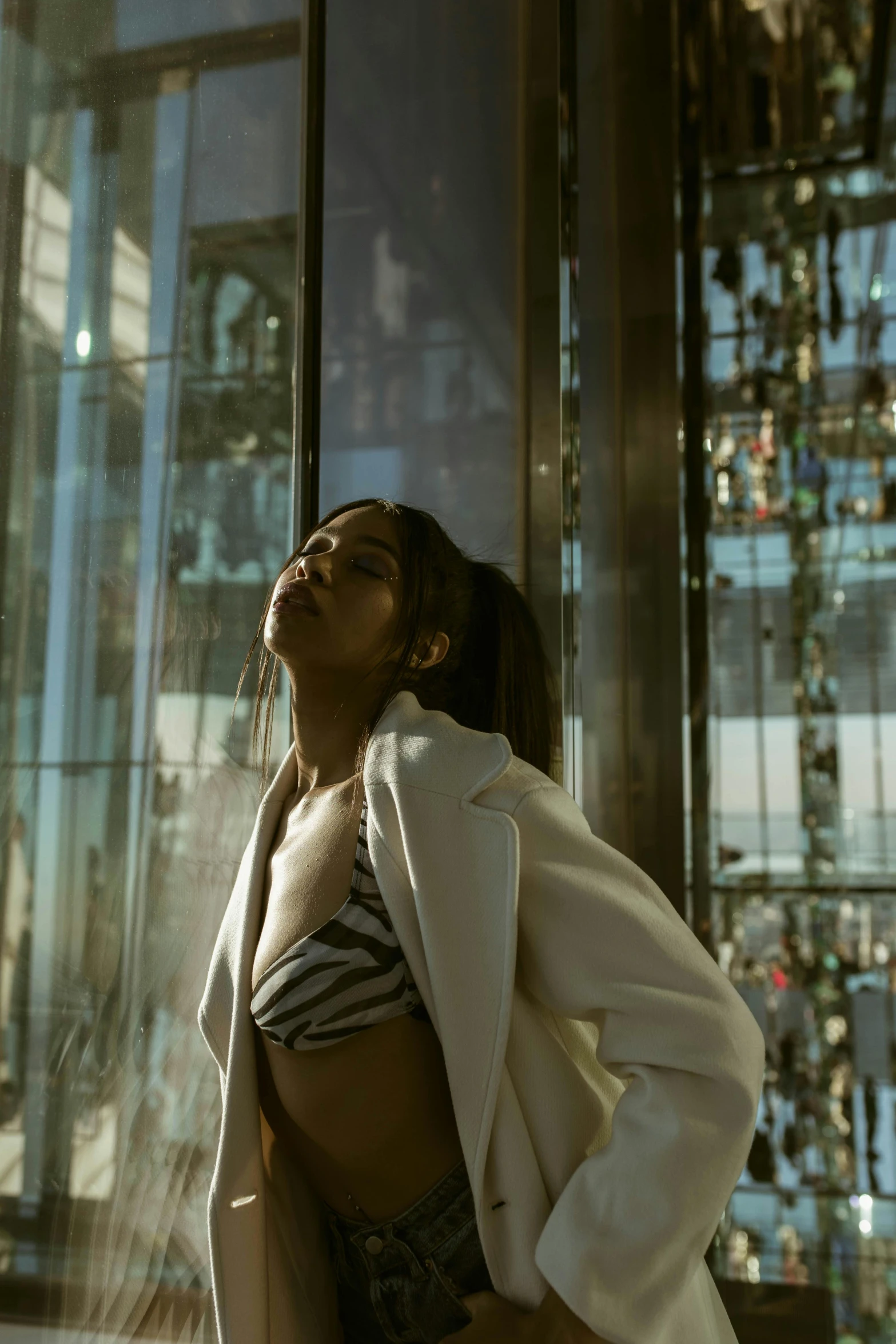 a woman standing next to a window in front of a glass building