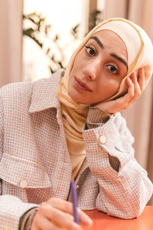 a woman sitting at a desk with her head wrapped over