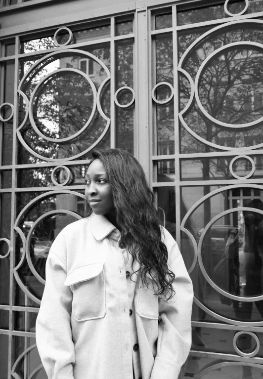 black and white image of a woman standing in front of a gate