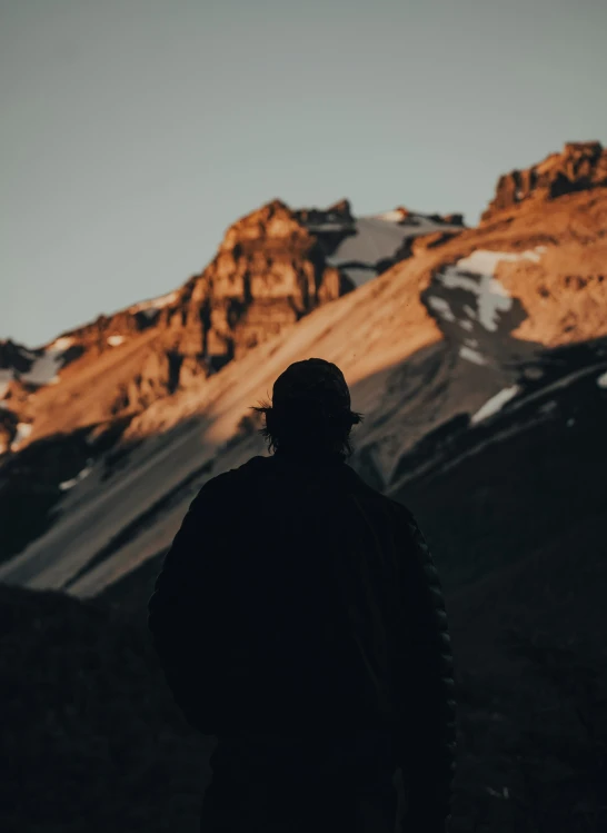 the man looks back at his companion as he walks past mountains