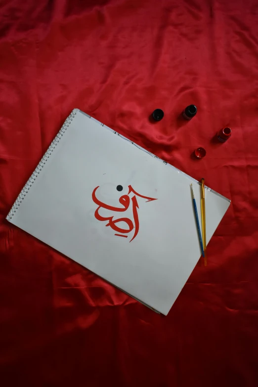 a red blanket on the ground with some art supplies