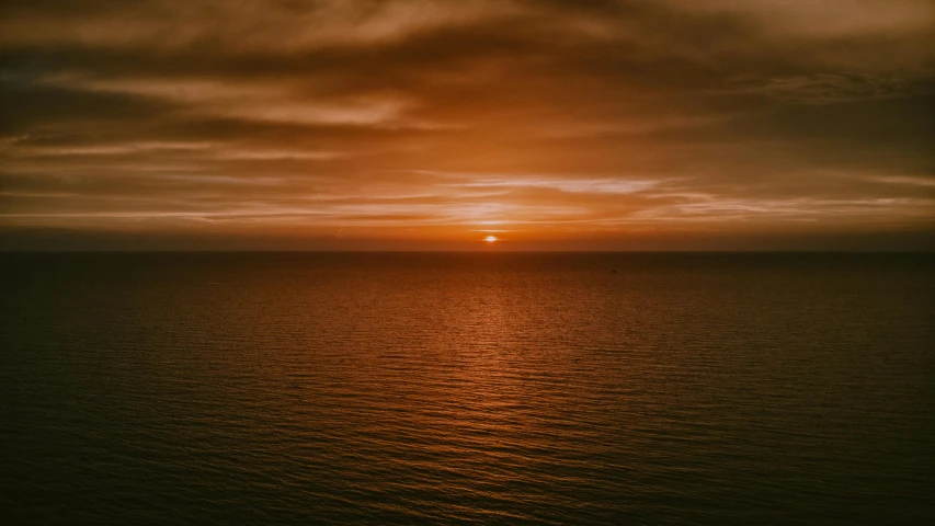 a sunset over the ocean with a boat in the distance