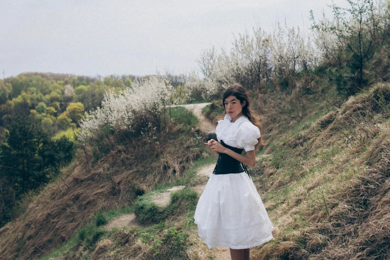 there is a woman in white dress walking on a road