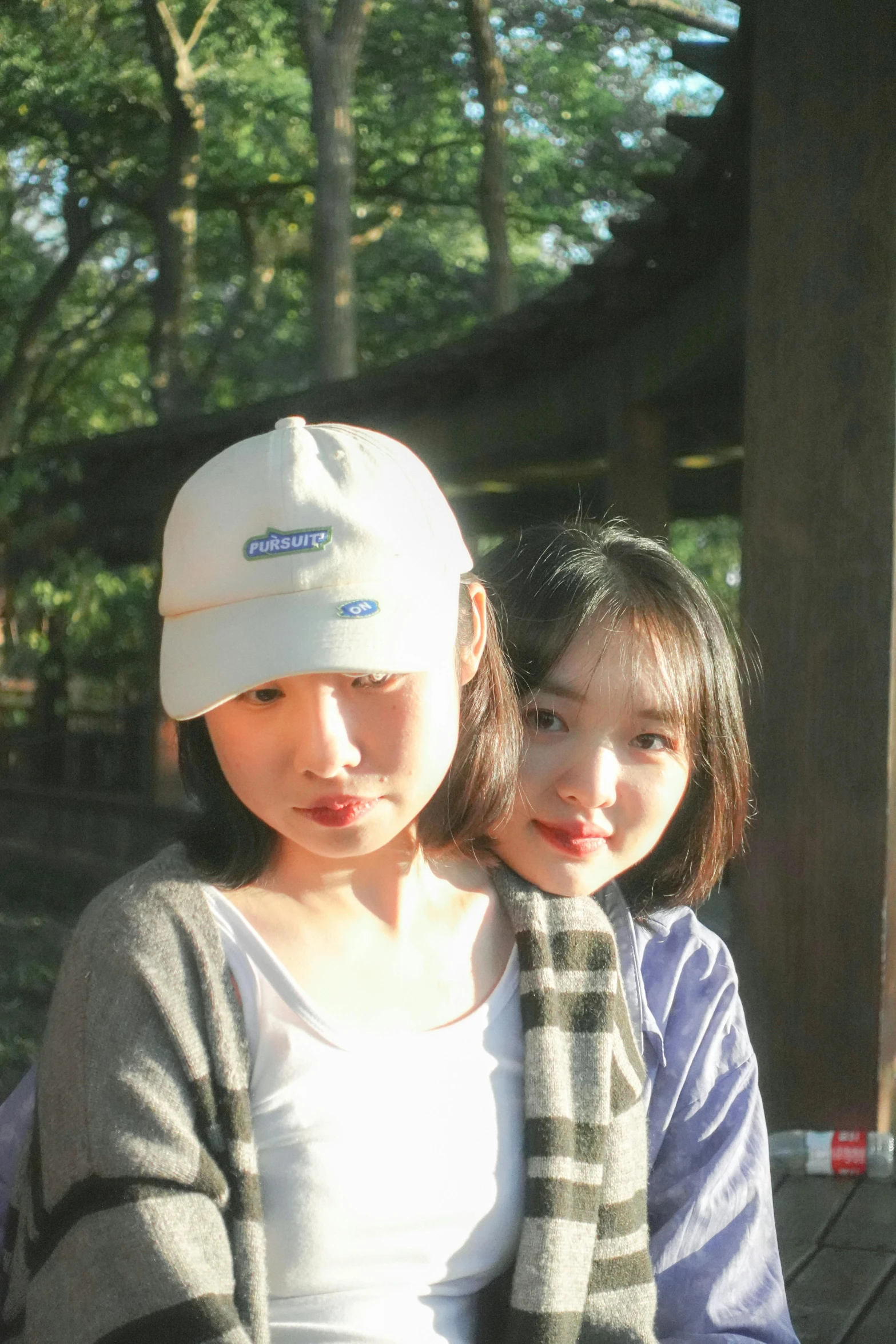 two girls pose for the camera while wearing hats