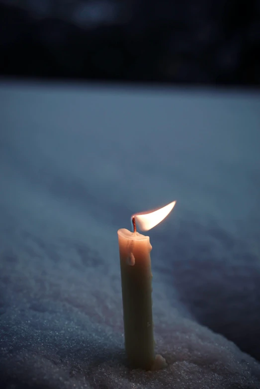 a small candle is on some snow at night