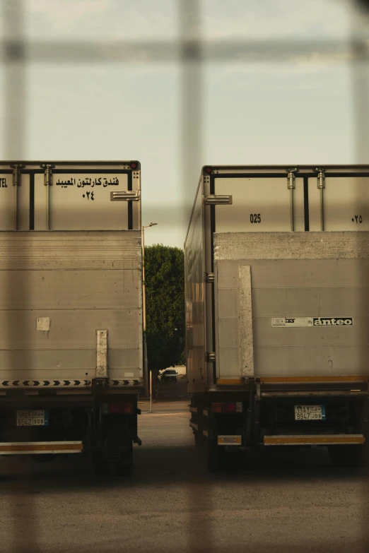 two trucks are parked behind a fence