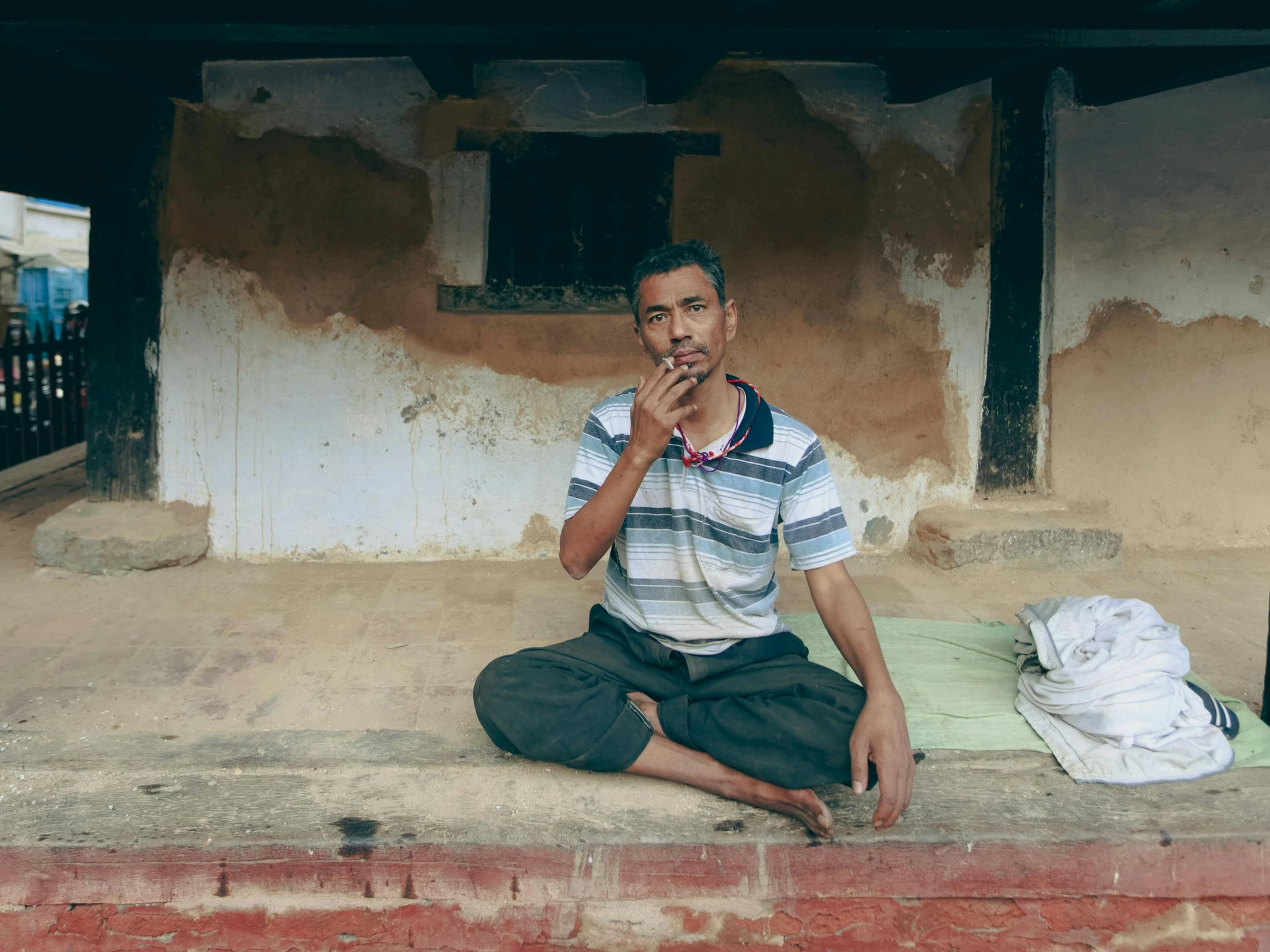 a man sitting on a step with a cigarette in his mouth