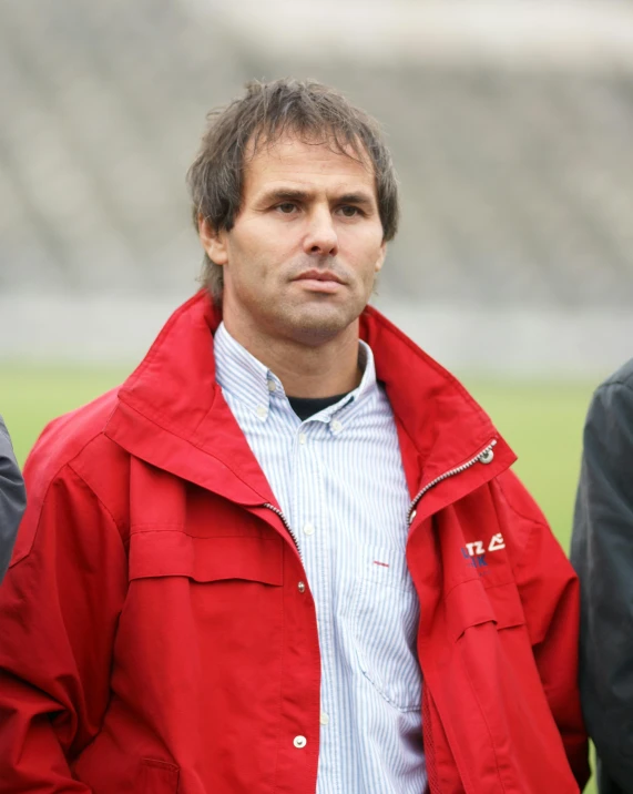 a man in a red jacket stands near others