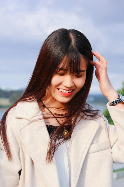 a woman posing with a necklace and wearing white