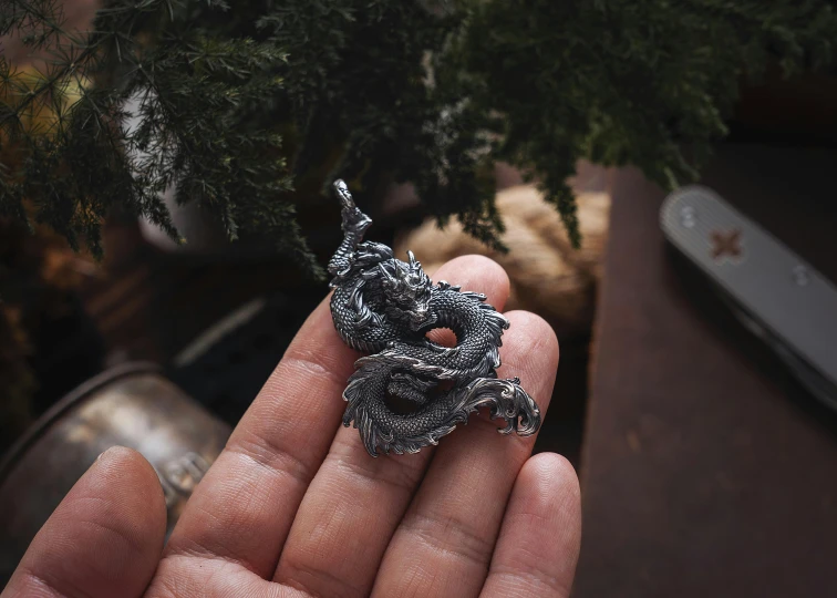 a small silver dragon ornament with wings curled up