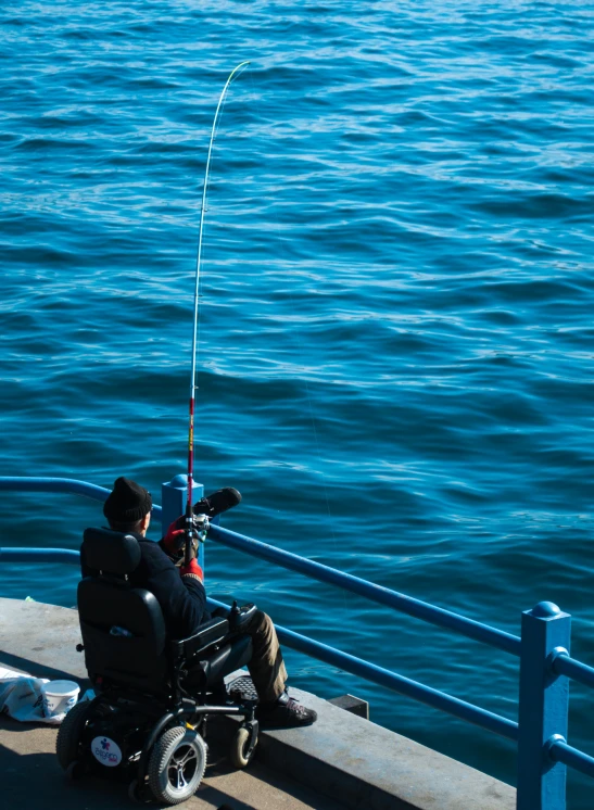 a man in a wheelchair fishing off the coast