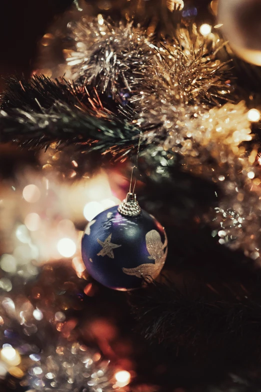 a christmas ornament hangs from the top of a pine tree