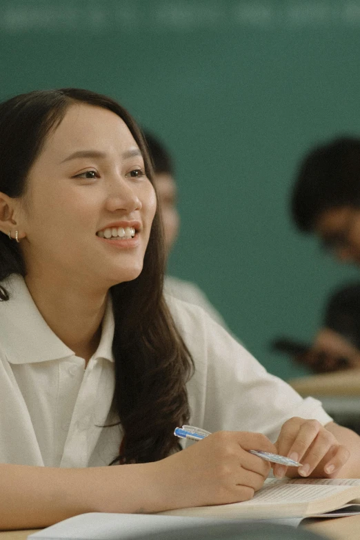 a beautiful young lady sitting in front of a table writing