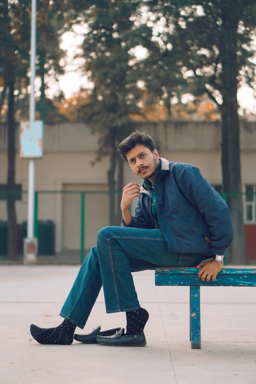 a man sitting on top of a blue bench in the city