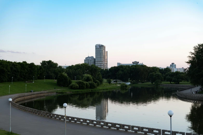 a large pond near the sidewalk that leads to the city