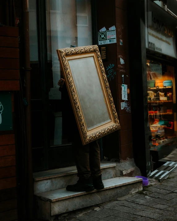 man holding up an old frame in front of a window