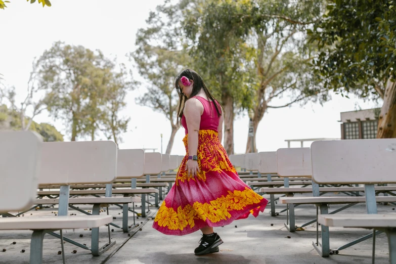 a woman in red and yellow dress walking by benches