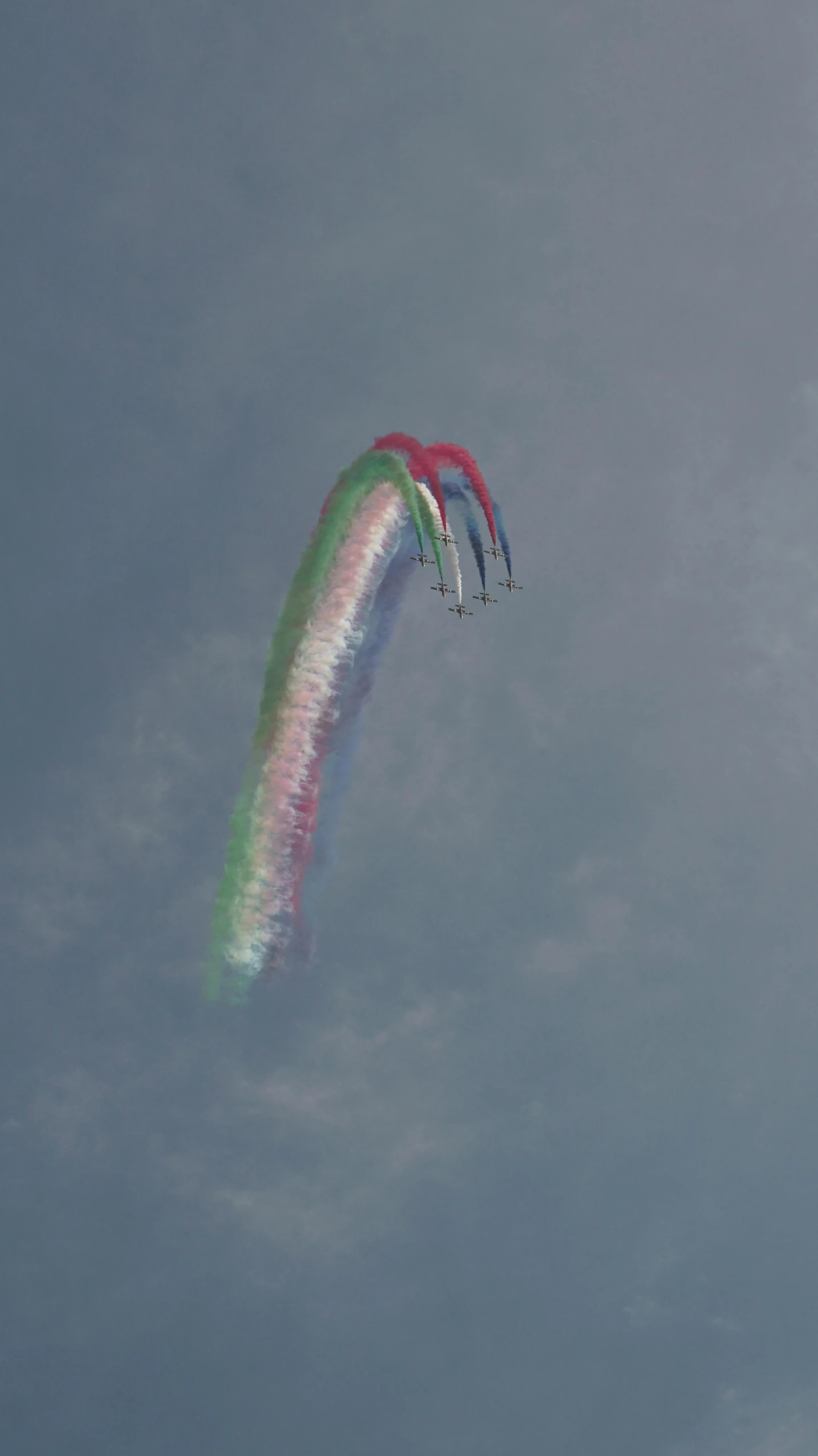 three colorful parachutes are in the sky with smoke coming out from it