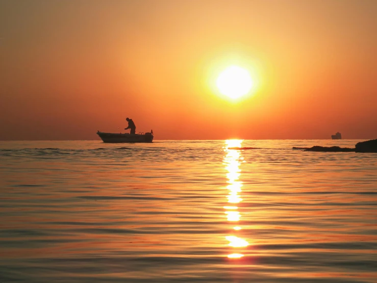 a man in a boat fishing in the middle of the ocean