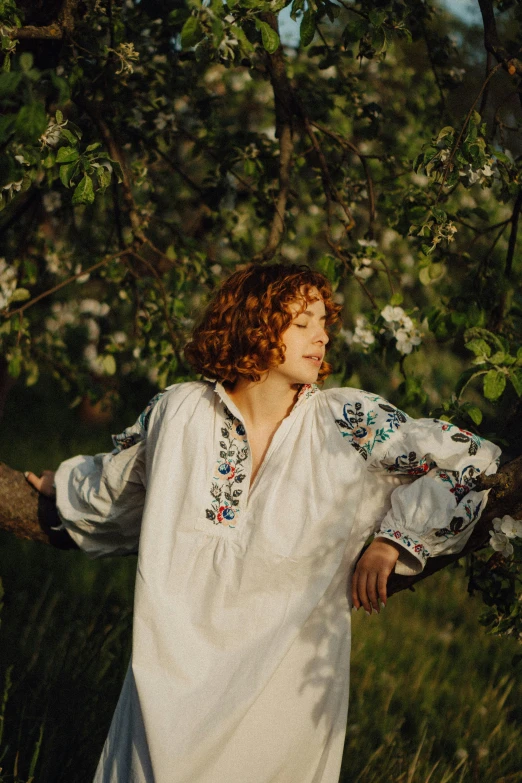 a woman with long red hair stands in a grassy area