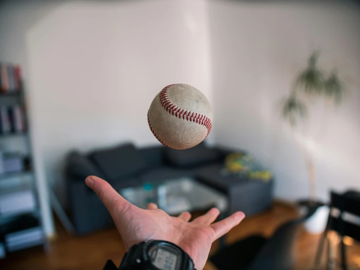 someone throwing a baseball in the air near a living room