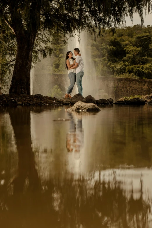 a man holding a woman standing in front of a pond of water