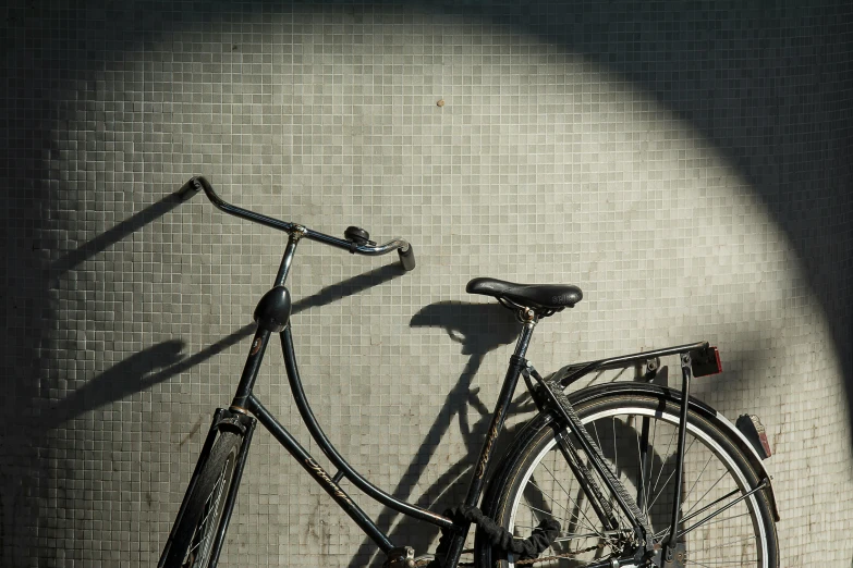 a black bike leaning up against a wall