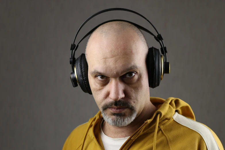 a bald man wearing headphones is looking at the camera