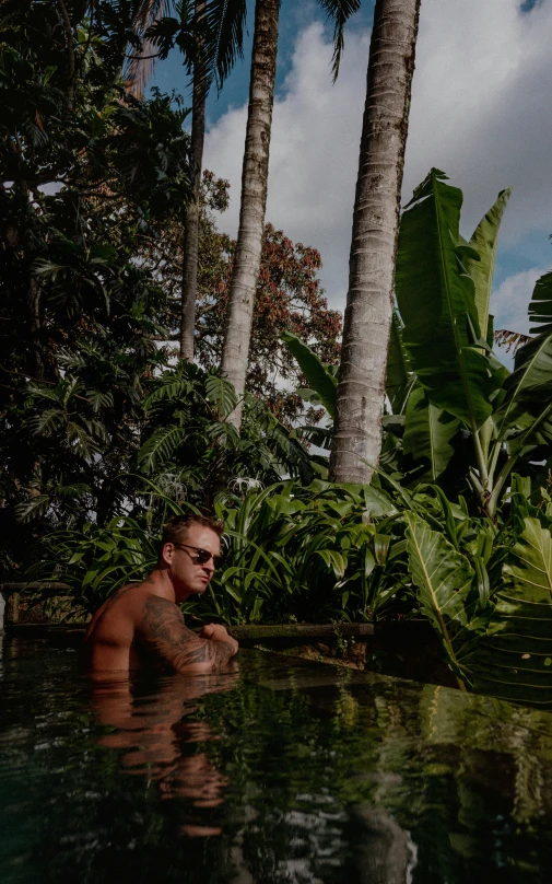a man in a pool surrounded by palm trees