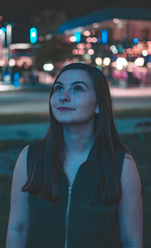 young woman standing in the middle of night looking into the distance