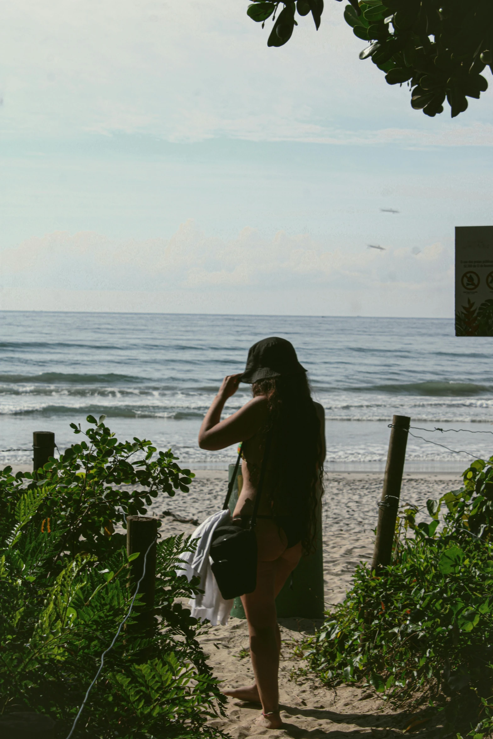 the woman is walking along the beach looking out at the water