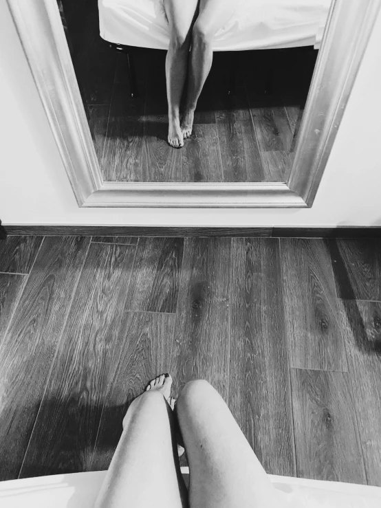 the woman's legs and feet are in front of the mirror